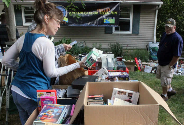 a woman checks out books at a yard sale