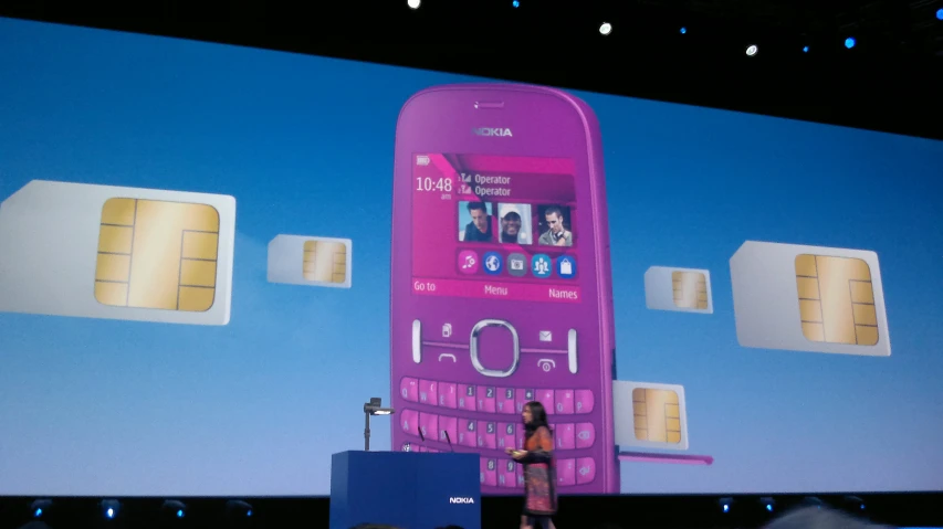 a woman in front of a giant pink cellphone