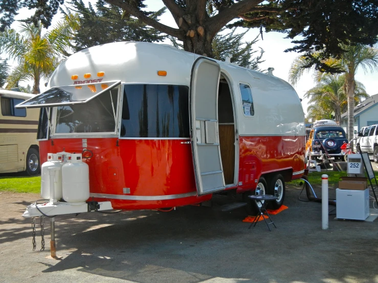 an rv sits under a large tree on the street