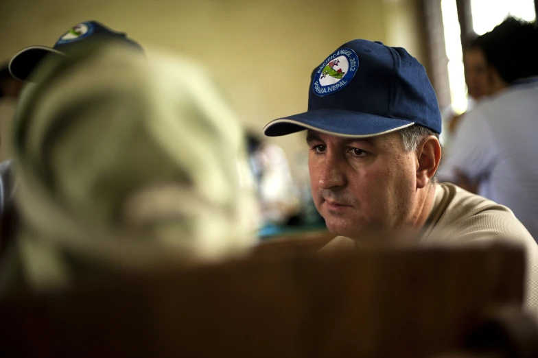 a man wearing a cap and sitting in front of other people