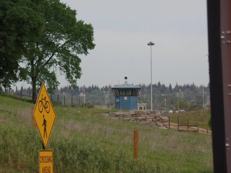 an upside down sign stands on the ground in a field near a signal tower