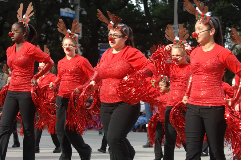 a group of women in red shirts and black pants walking down the street
