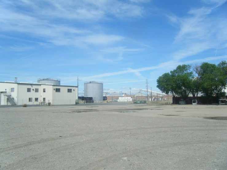 empty parking lot with two trees and a large warehouse