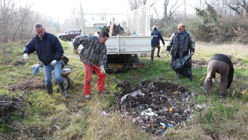 a group of men work with the garbage in a field