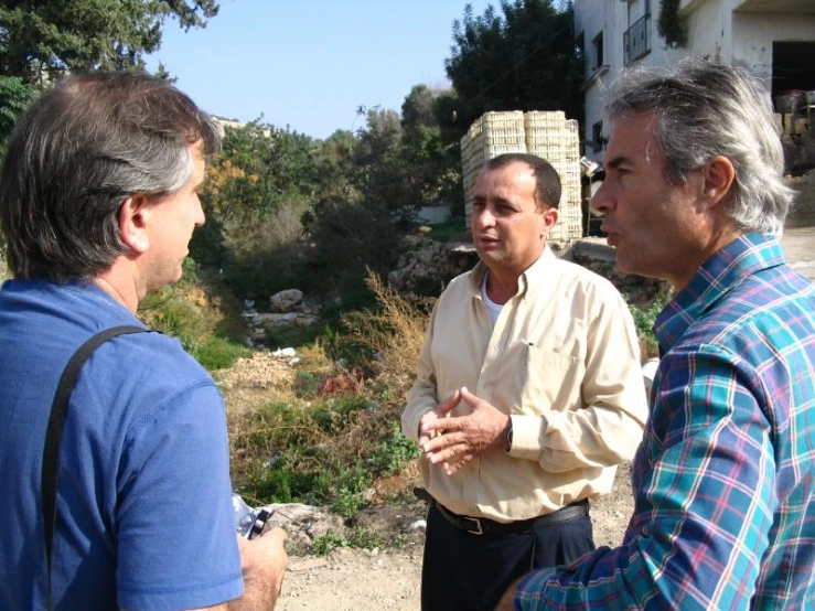 two men talk with another man on the other side