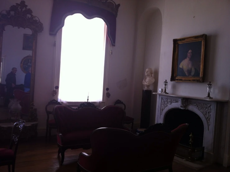 the view from a room with three sofas, fireplace and a statue in the window