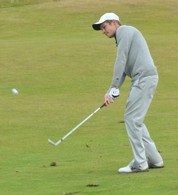 a man holding a golf club up to hit the ball