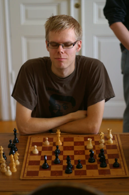 a man sitting at a table with chess pieces