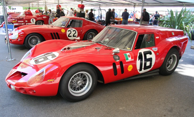 several old style cars parked under a tent