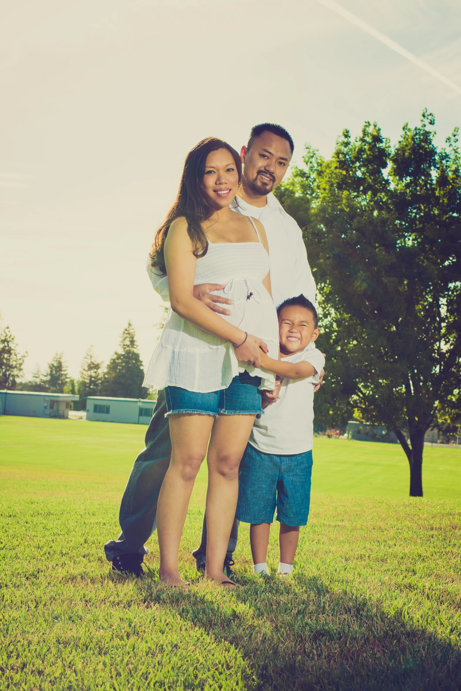 a young family standing in the grass with one child