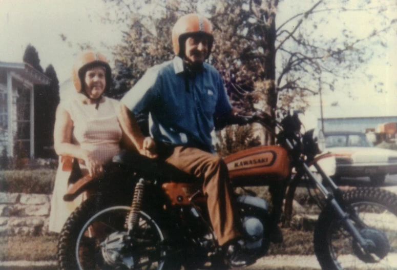 an old picture of a man and woman on a motor bike