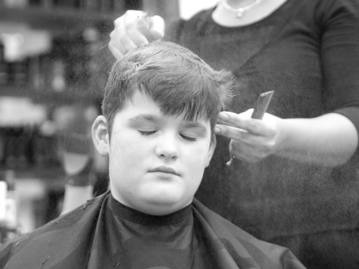 black and white pograph of a little boy getting his hair cut