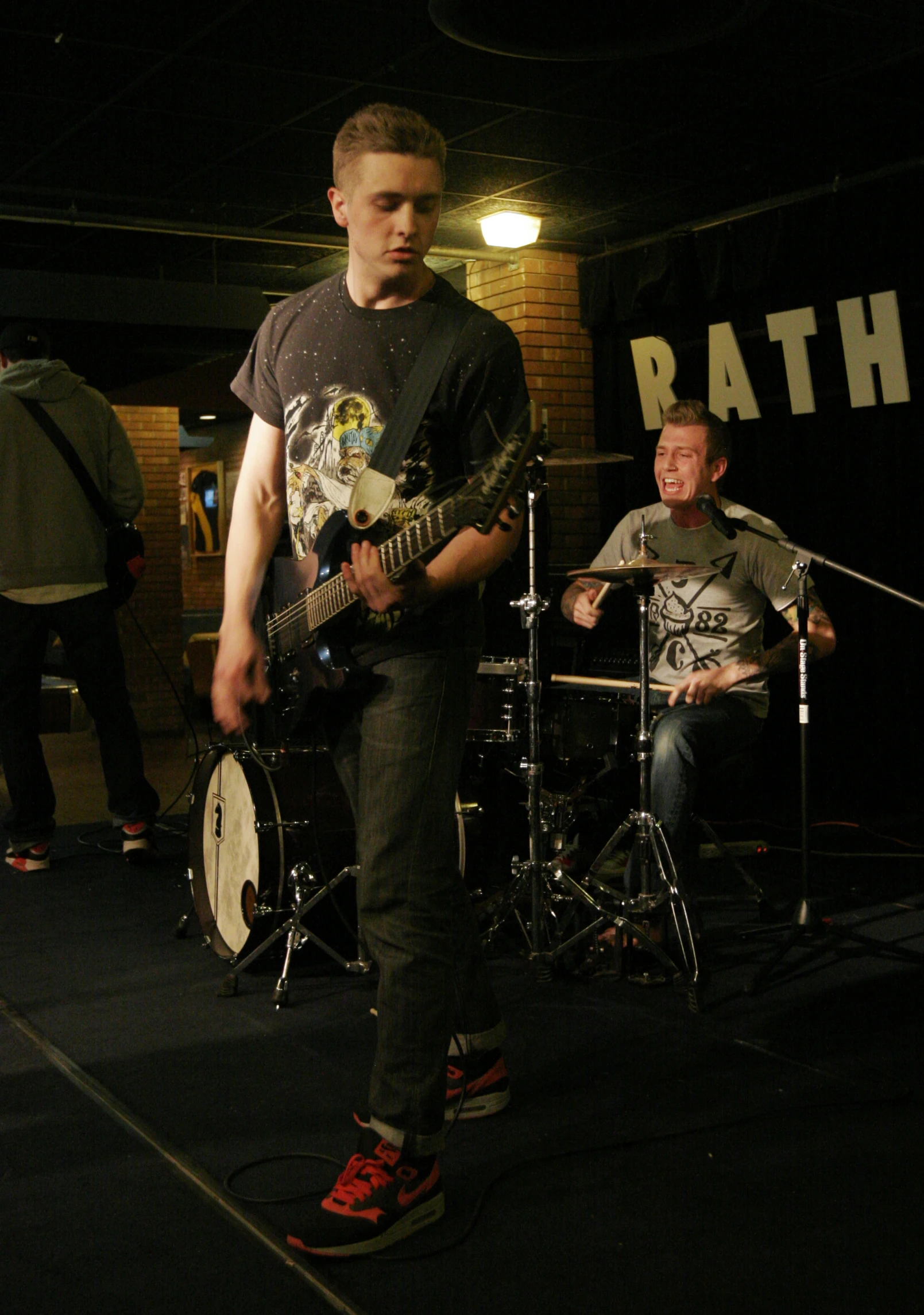 the young man is playing the guitar and another man on stage