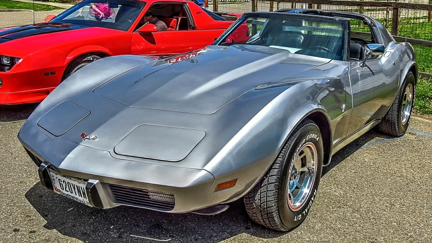 two vintage corvette cars are lined up in a parking lot