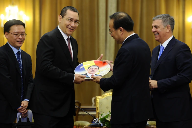 three men in suits standing around each other and smiling