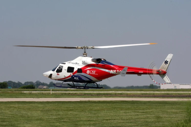 a white and red helicopter on runway in open field