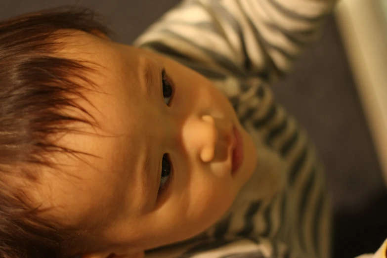 a baby holding soing with his hands with the camera around him