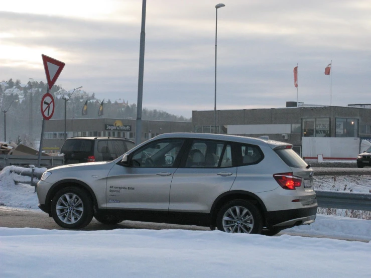 a silver car parked at a road sign covered in snow
