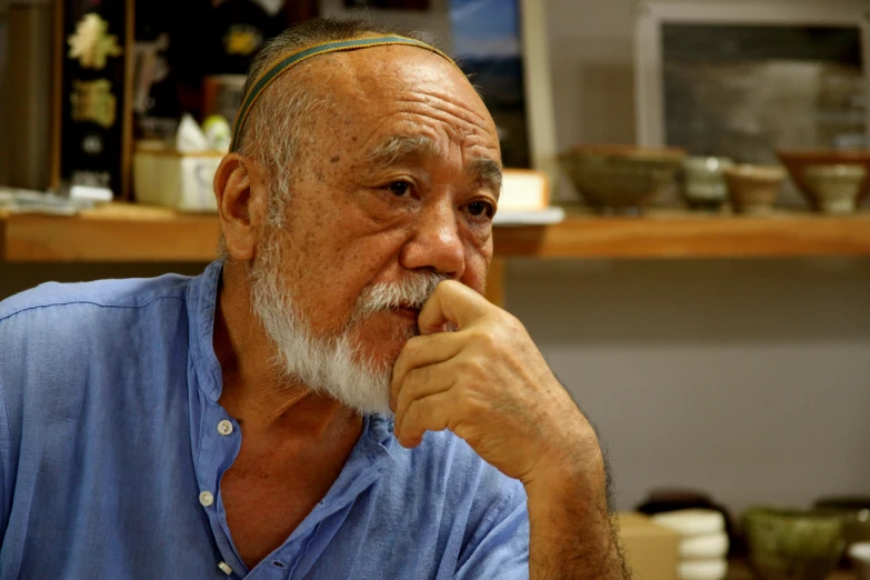 an old man with a beard and glasses sitting in front of a kitchen counter