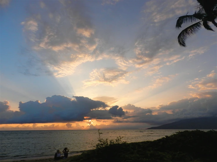 people are on the beach at sunset while the sun is down