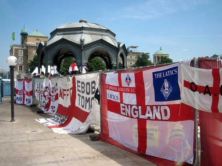 several banner banners that say england next to a fence