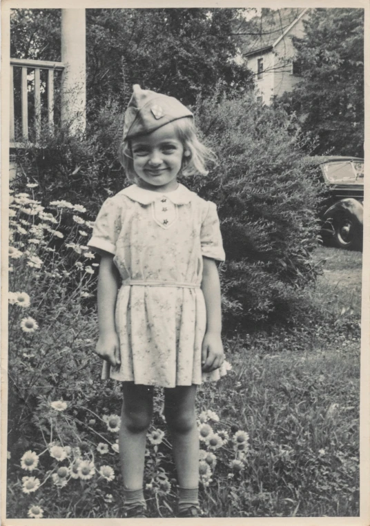 a little girl standing in front of some flowers