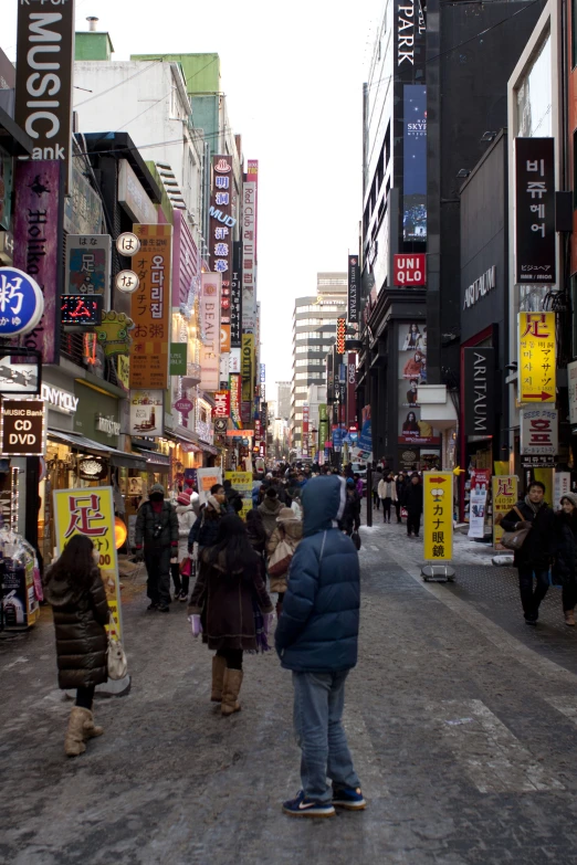 many people are walking down a crowded street in a city