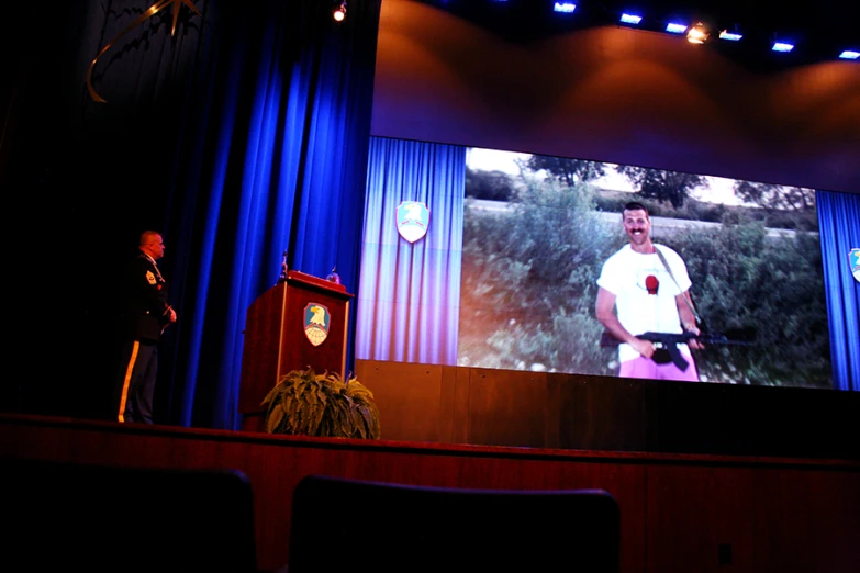 two men standing in front of a big screen display