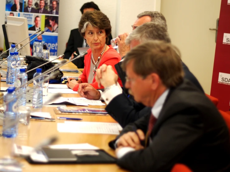 people sitting at a table listening to a speaker