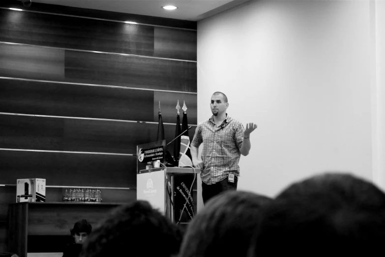 black and white image of man giving lecture to audience