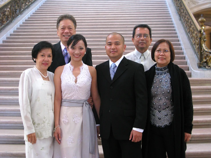 six people wearing formal attire standing in front of some stairs