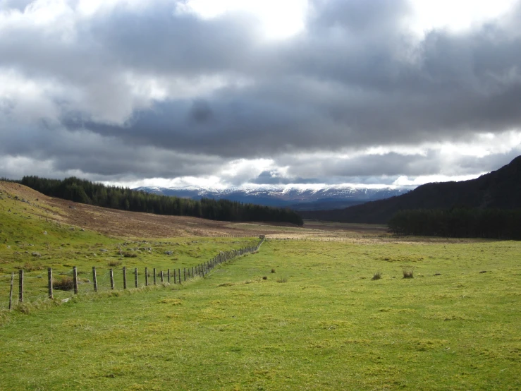 a po of some grass hills and a fence