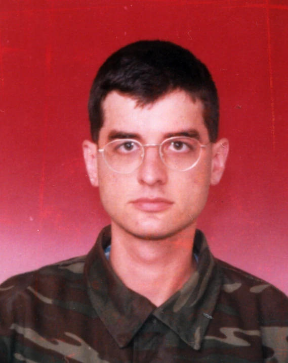 a man in glasses and camo shirt looks at the camera