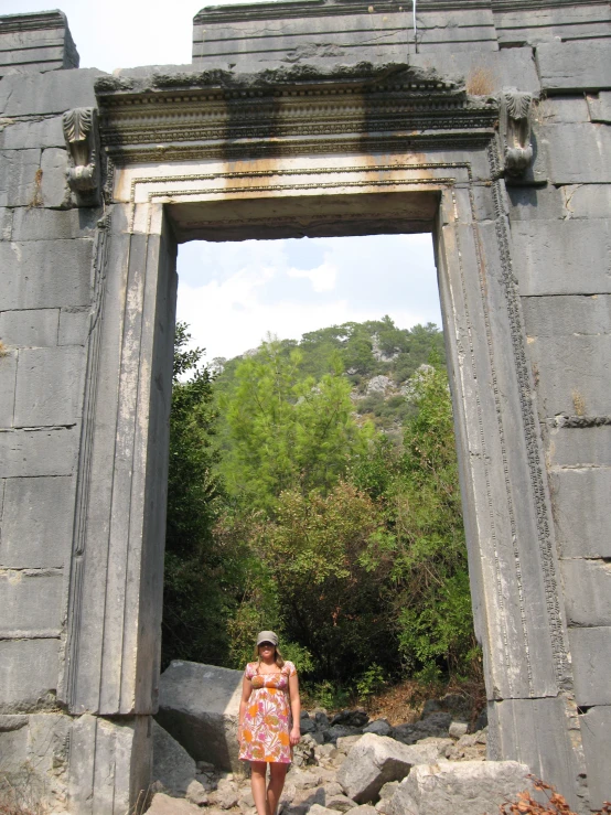 a woman wearing a hat standing between two stone pillars