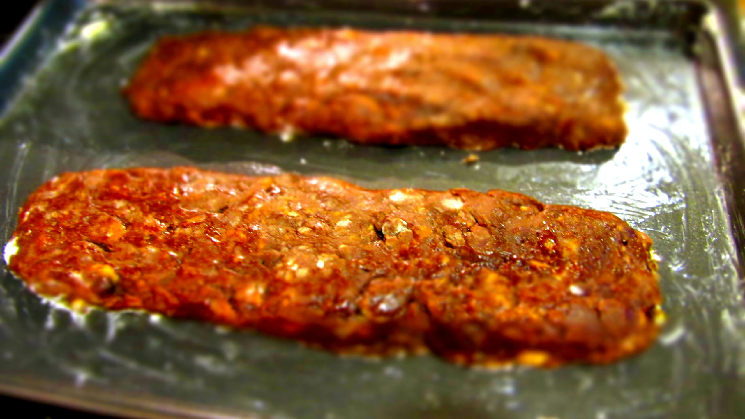 two pork chops being cooked on a pan