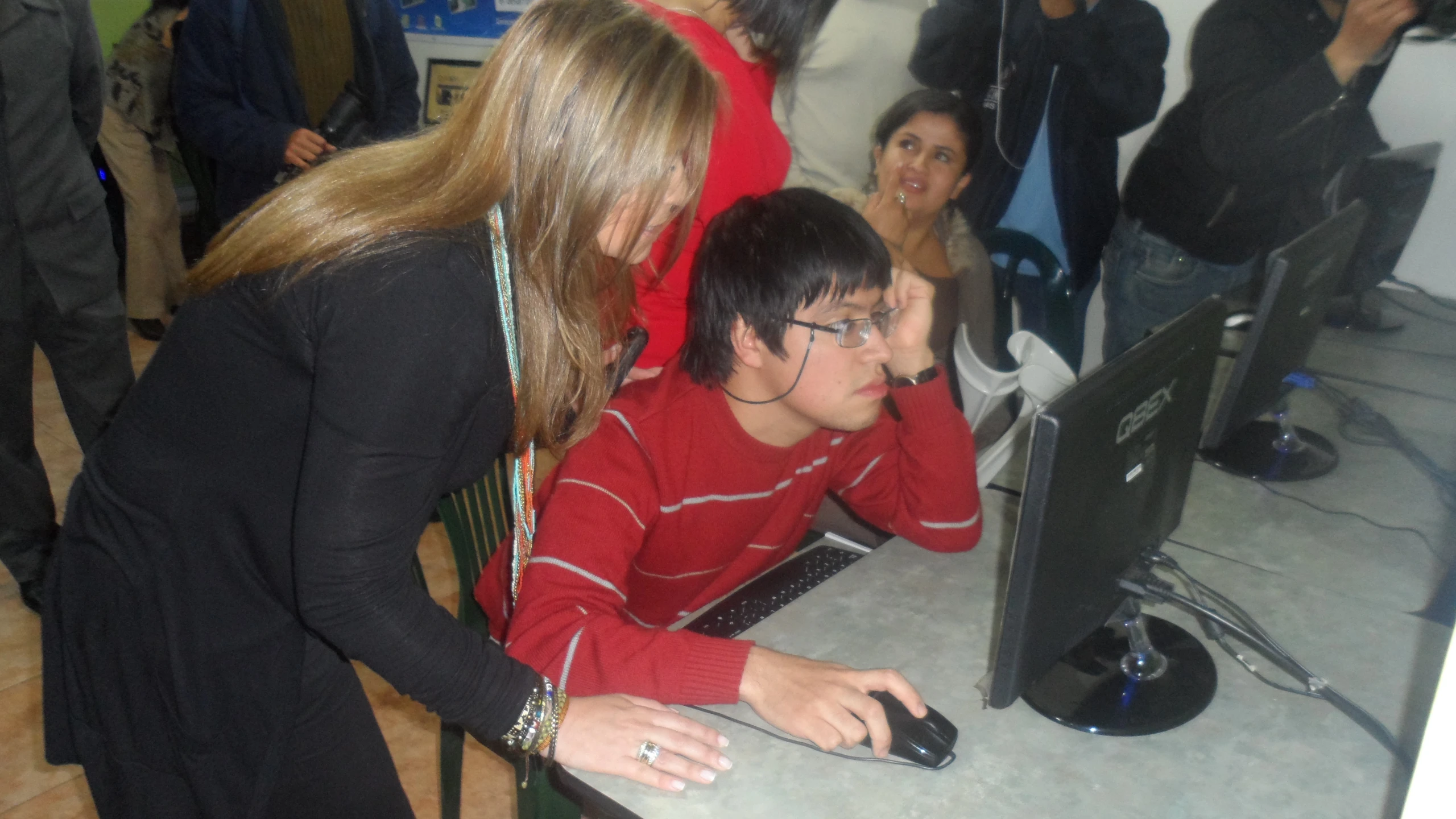 a woman looking at a young man in front of a computer monitor