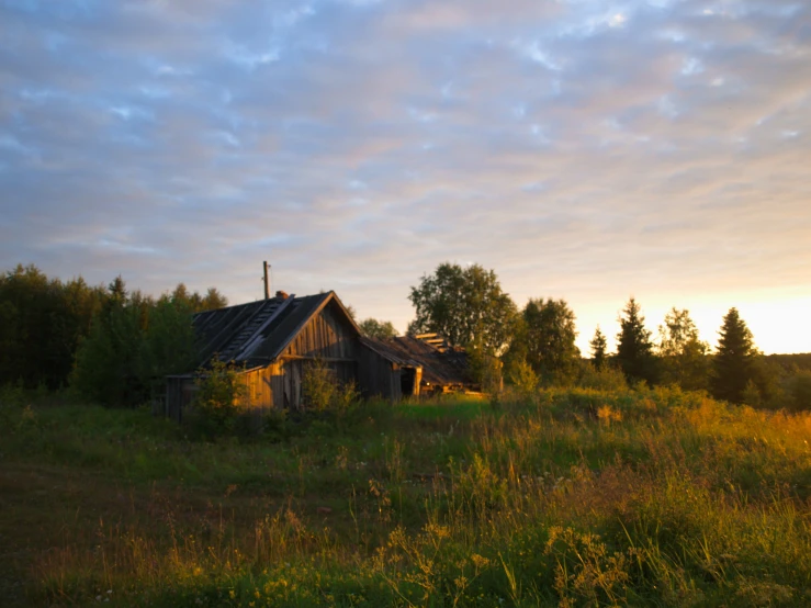 an old house that is in a field at sunrise
