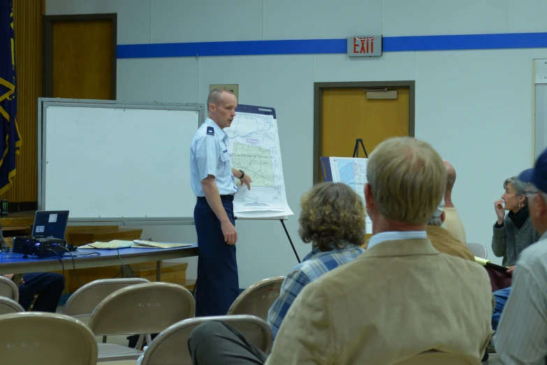 an officer stands next to a board in front of people