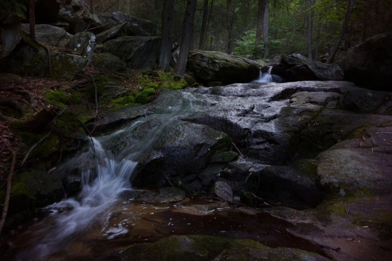 a waterfall running over rocks into a forest