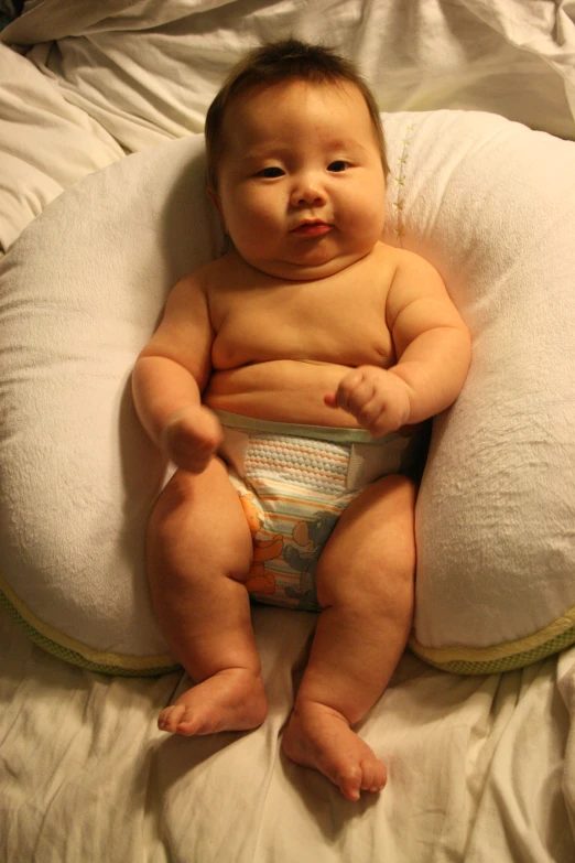 a baby in diapers sitting on a pillow