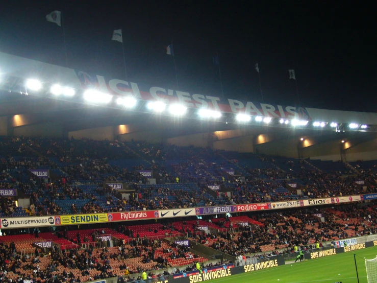 a large crowd of people sitting on a field in front of an arena