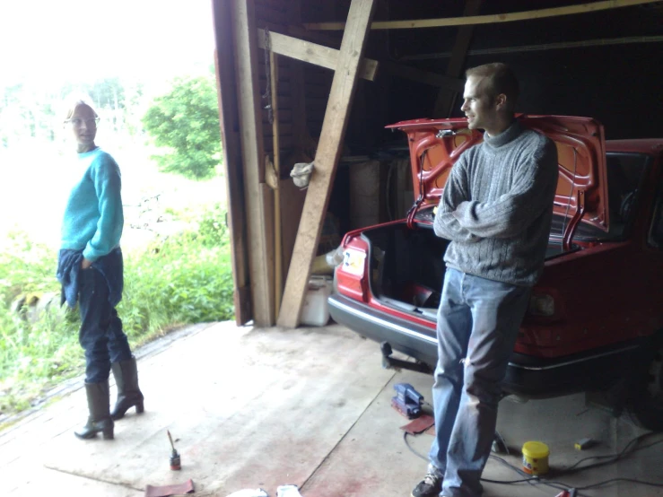 two men standing in the shed looking in the car door