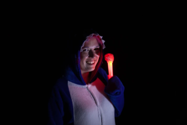 a woman in the dark holding a lit up toothbrush