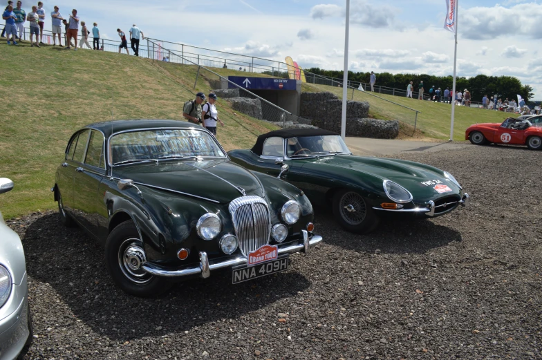 two vintage automobiles sitting parked on a parking lot