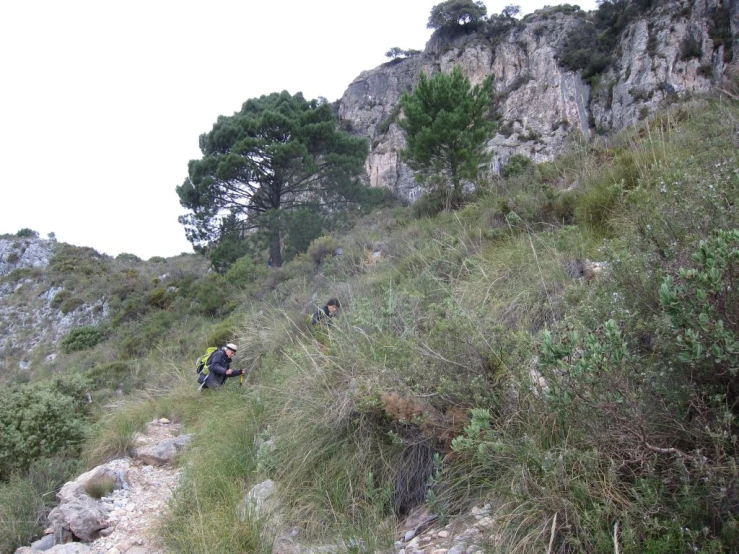 three hikers are climbing up the side of a hill