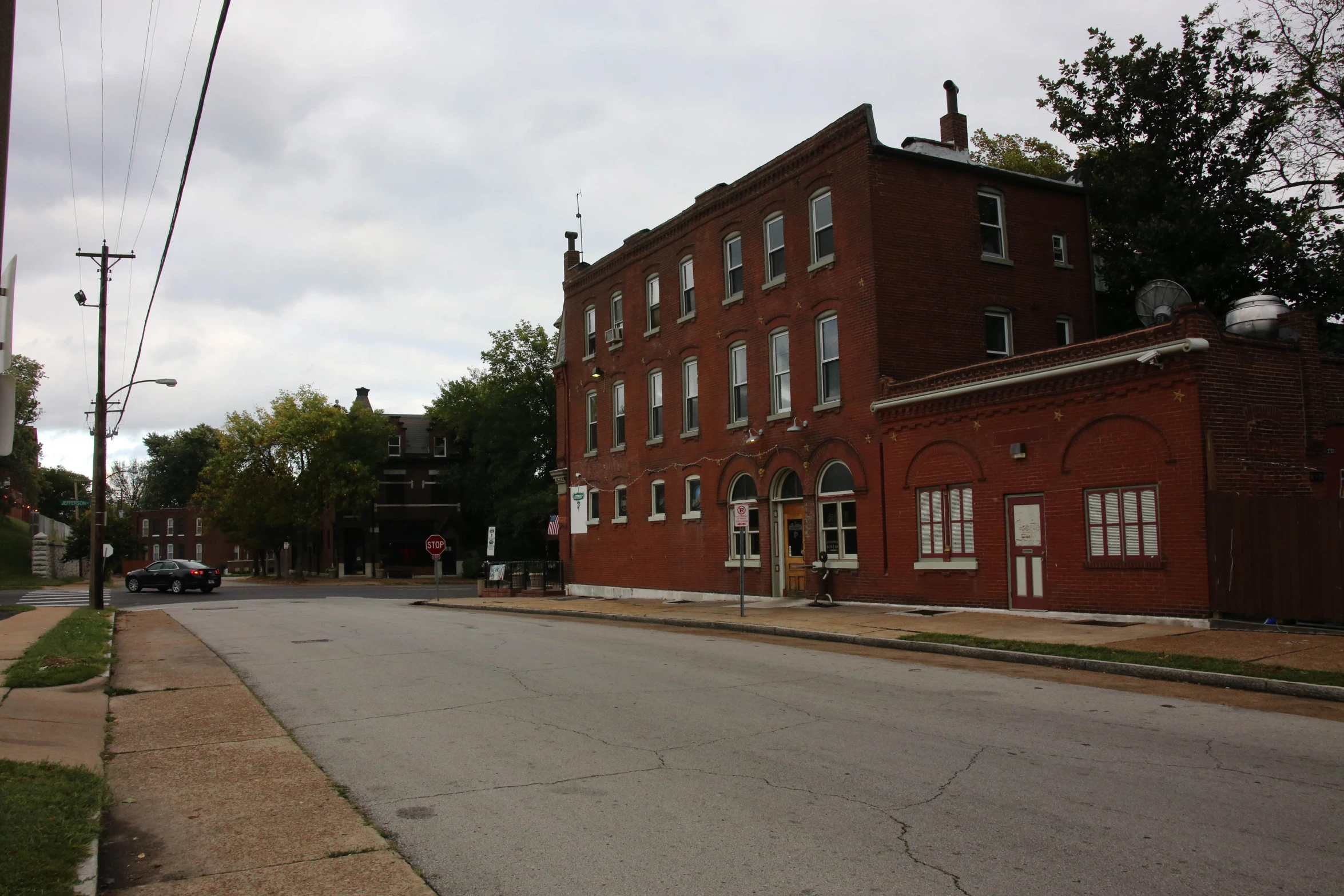 a red brick building with white windows is on a quiet street