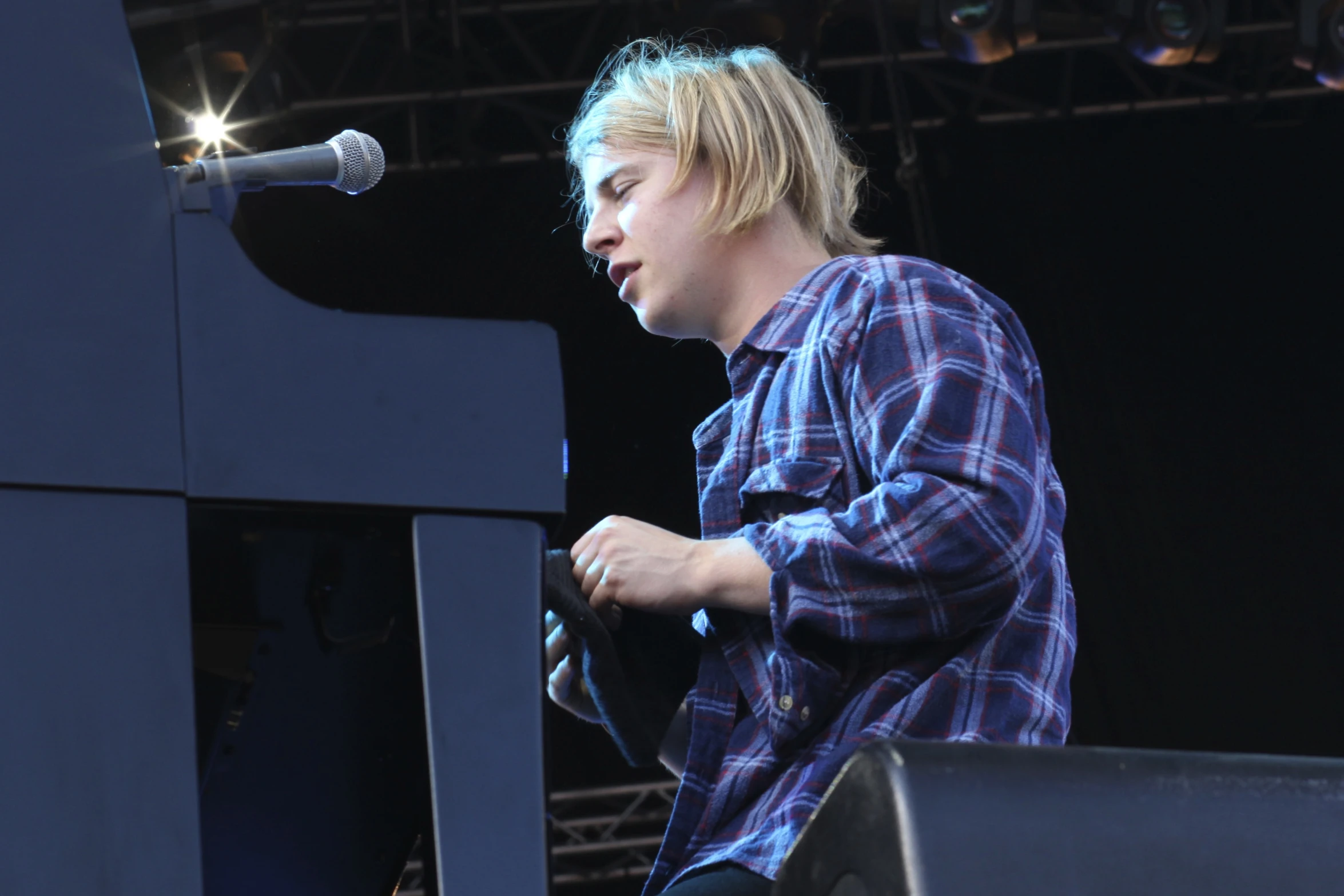 man in plaid shirt playing the piano at a concert