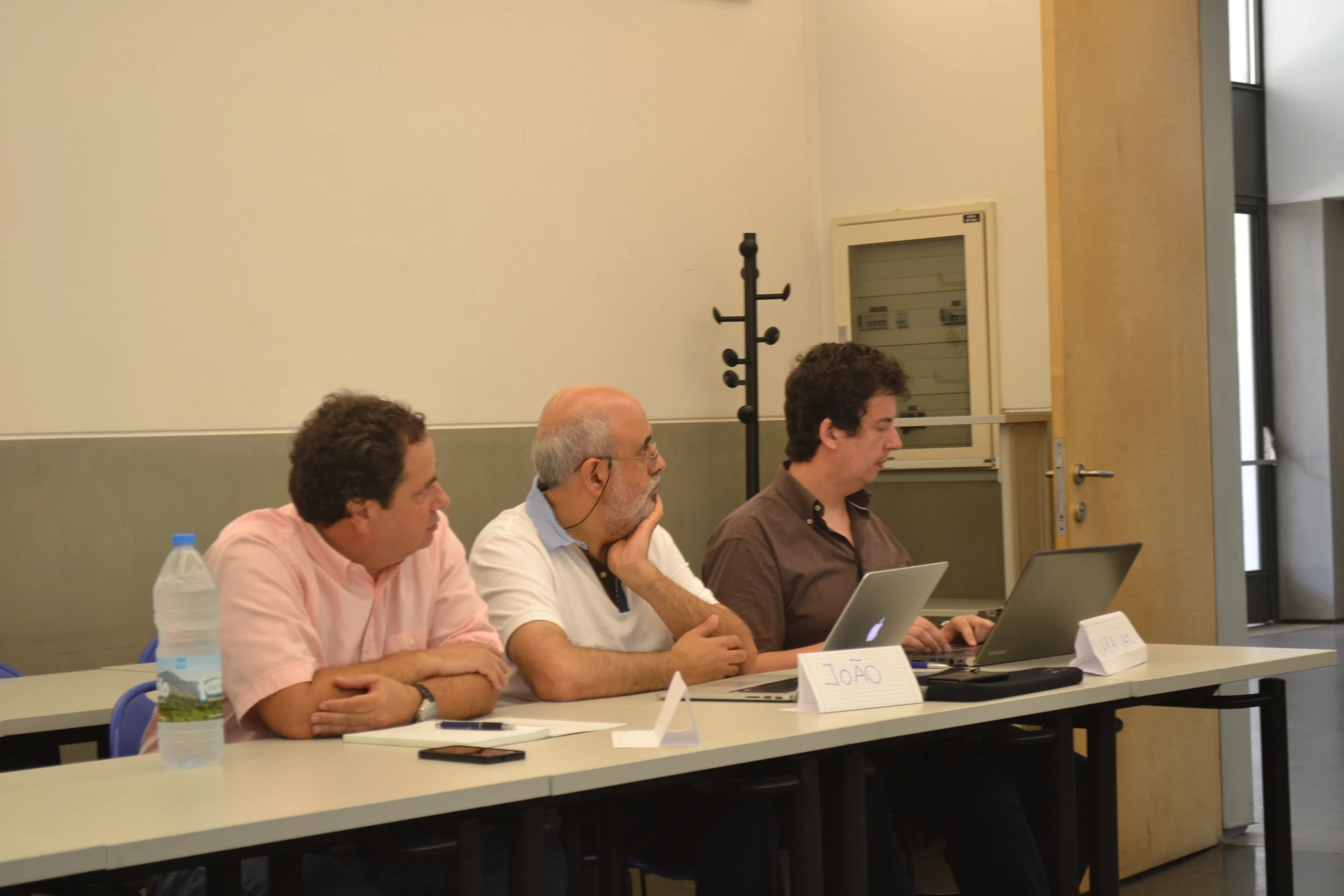 three people sitting at a table while looking at their laptops