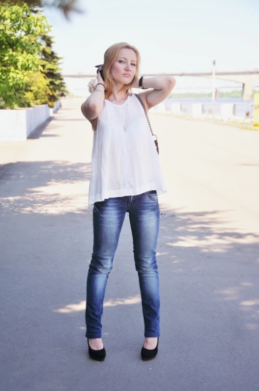 a woman wearing blue jeans and a white top