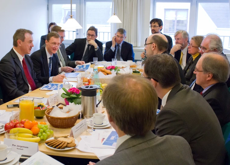 many people sitting around a table together eating